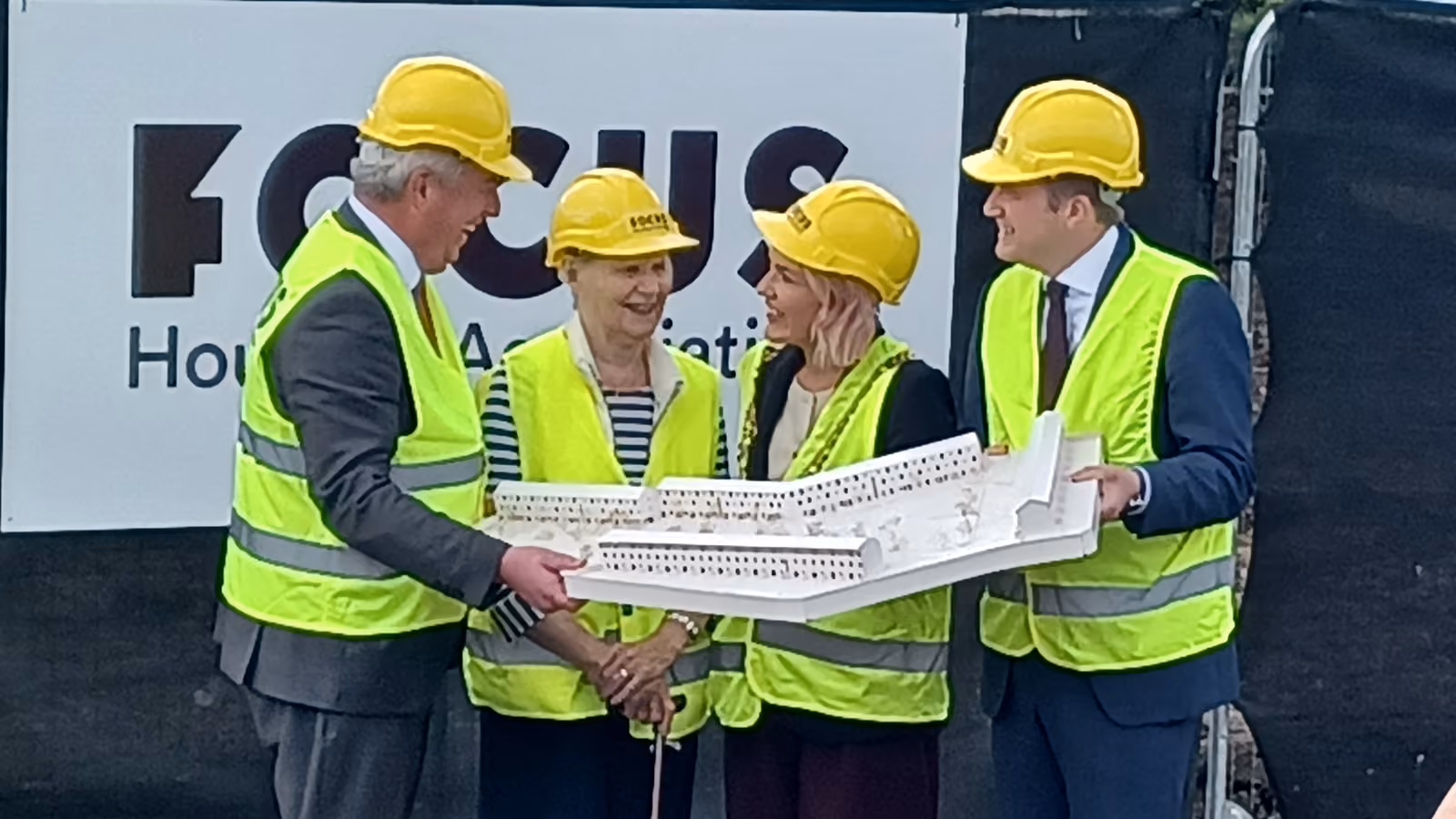 Four people wearing high-vis jackets and hard hats