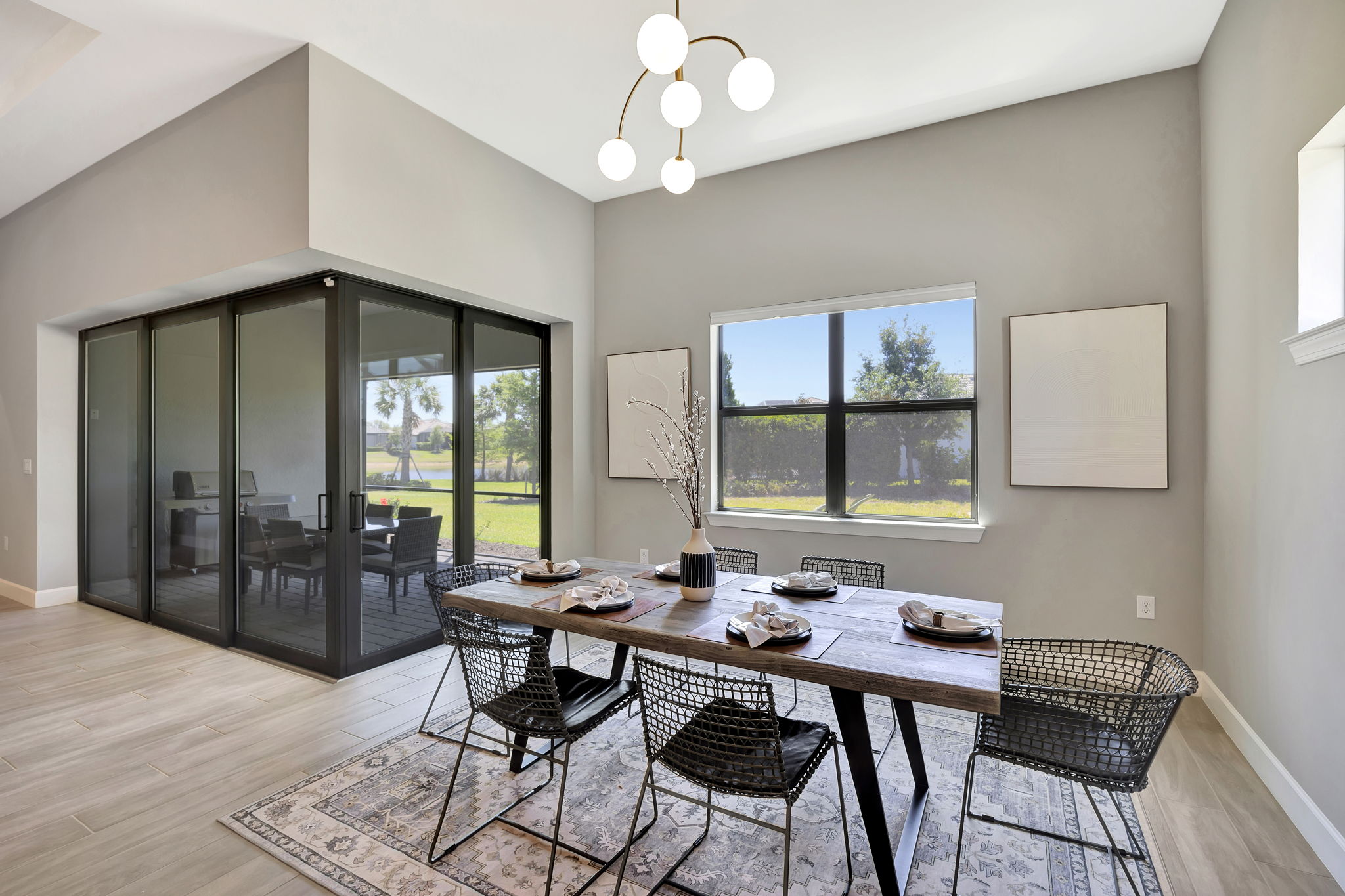 Modern dining room with garden view, elegant table setting, chandelier, and glass doors for stylish Florida vacation renta...
