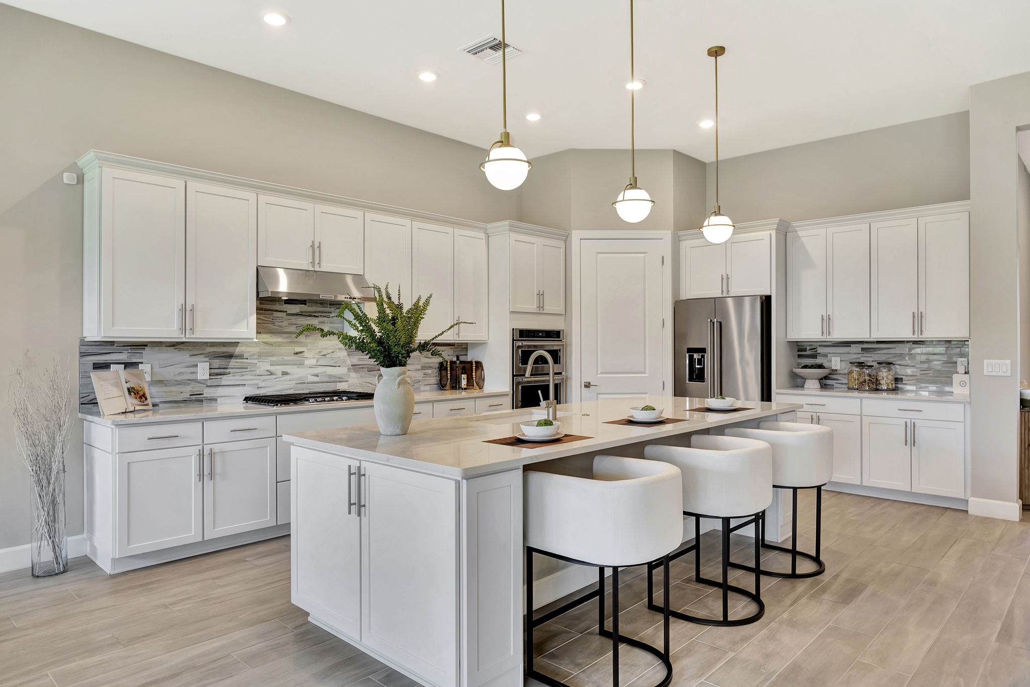 Modern kitchen with large island, bar stools, pendant lights, stainless steel appliances, and stylish decor in luxury Lake...