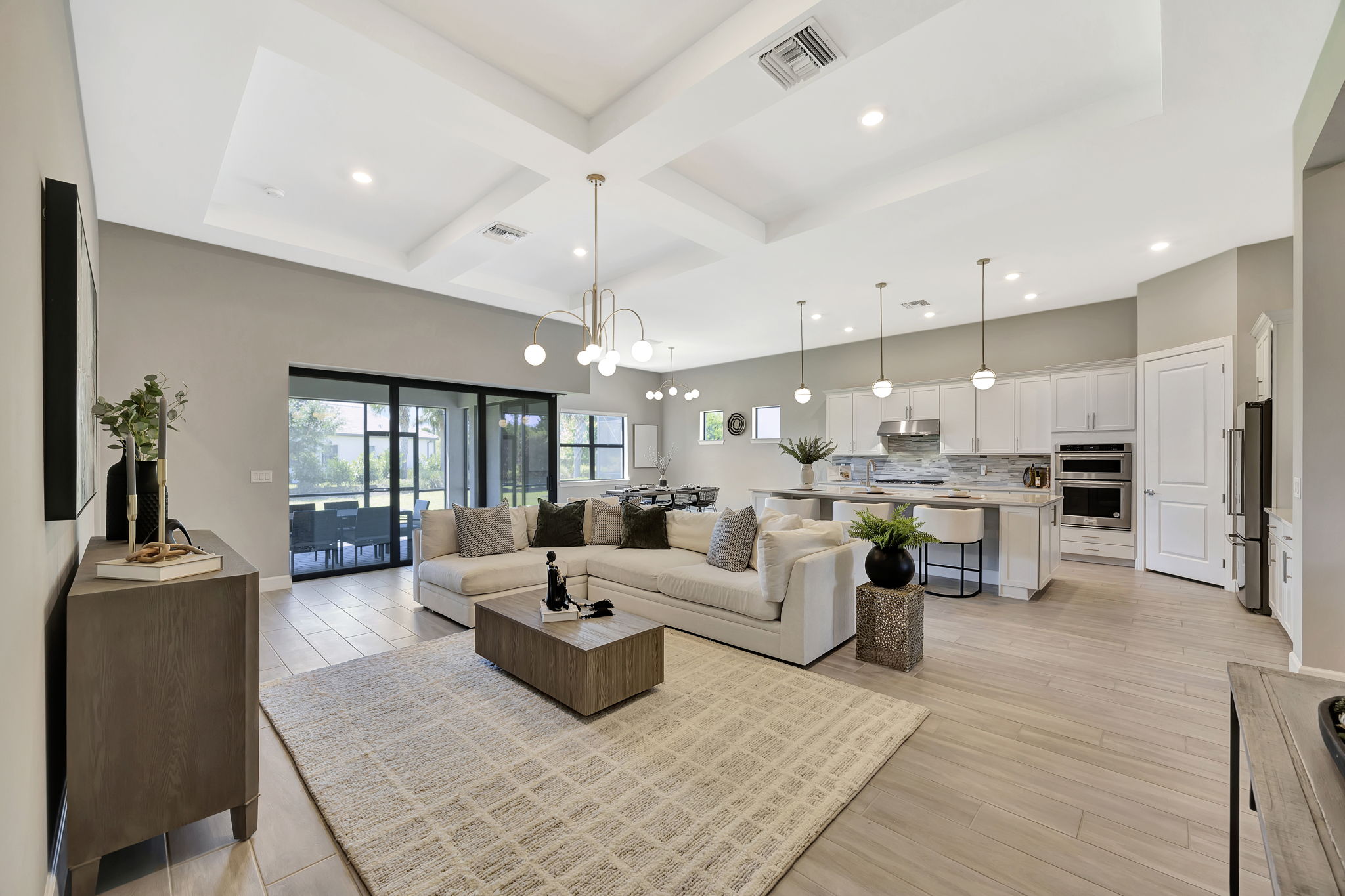 Modern open-concept living room and kitchen with sofa, island, pendant lights, and bar stools showcasing stylish home decor.