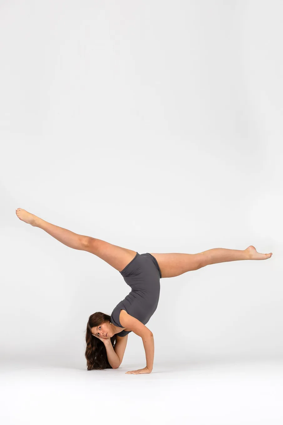 Danceology dancer in a handstand on one hand with legs split wide