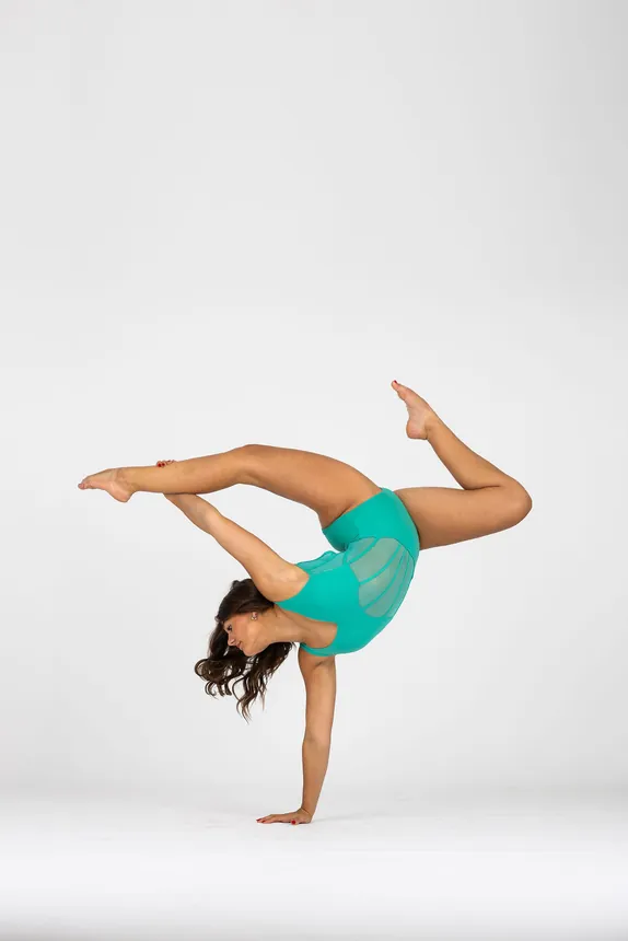 Danceology dancer in teal balancing on one hand with her legs in a shaped split