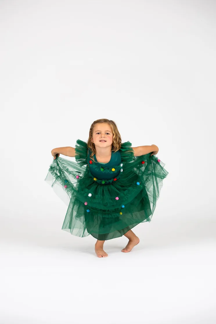 Little Danceology dancer in a green tutu dress holding out her skirt and smiling