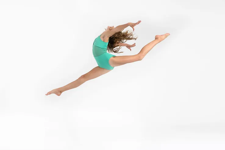 Teen Danceology dancer in a teal leotard in a split leap