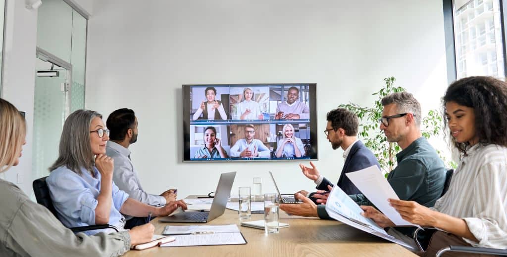 Hybrid business meeting with in-person and remote team members via video conference