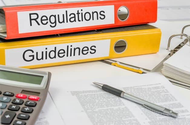 Binders labeled Regulations and Guidelines with calculator and pen