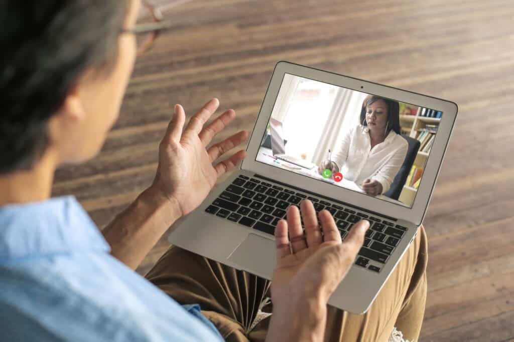 Person having a video call on laptop with another person in office