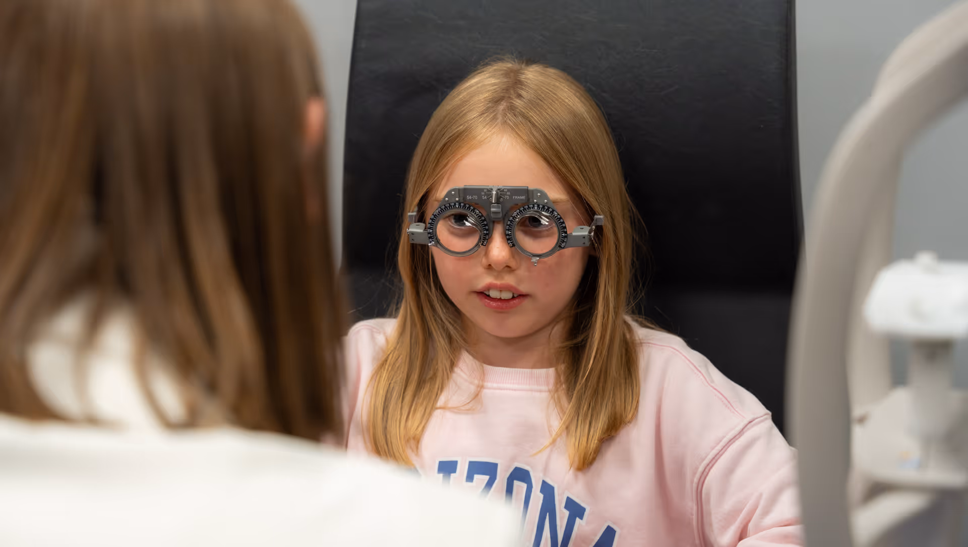 Child wearing trial frame during eye exam in medical office