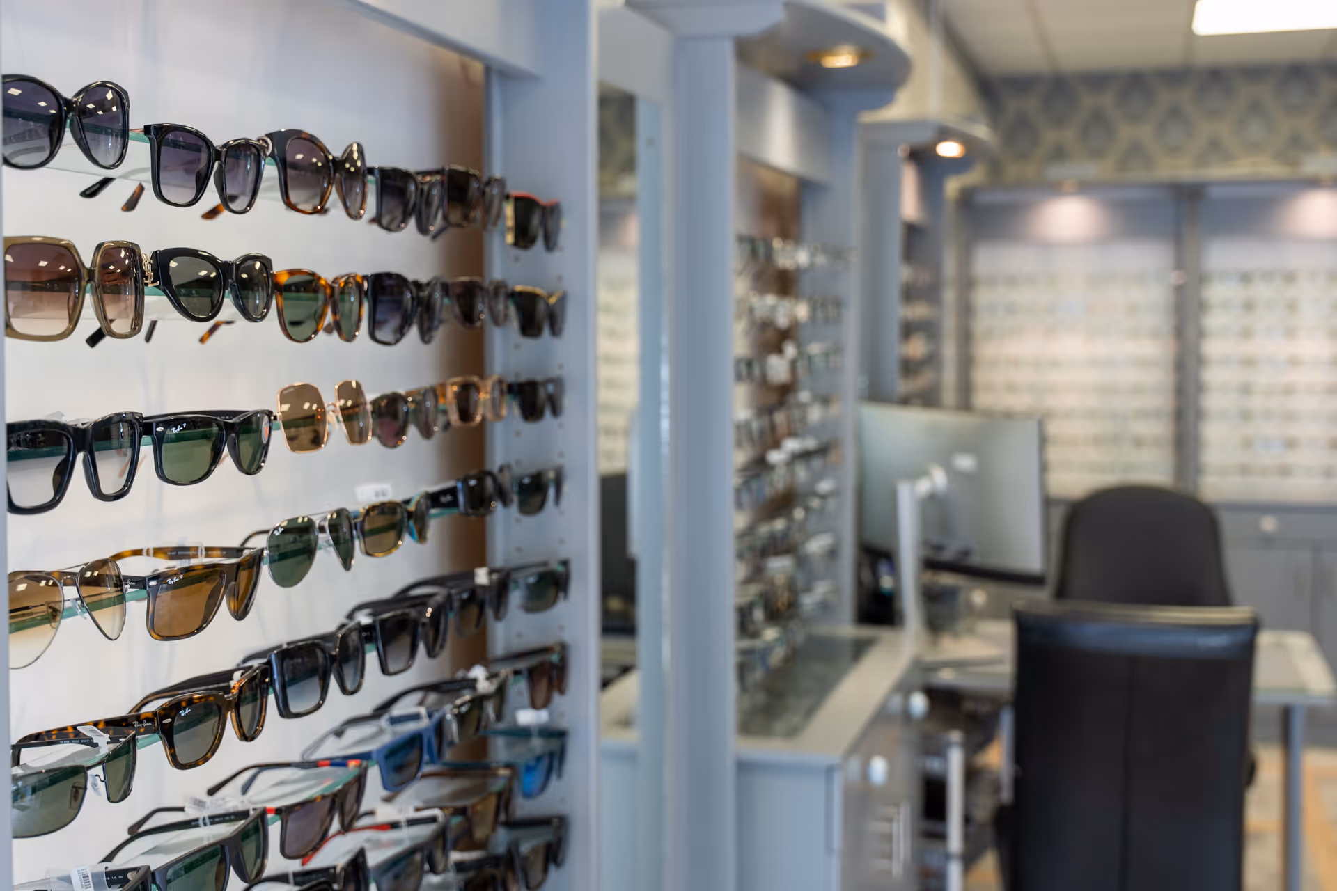 Display of various sunglasses on wall in optician's office