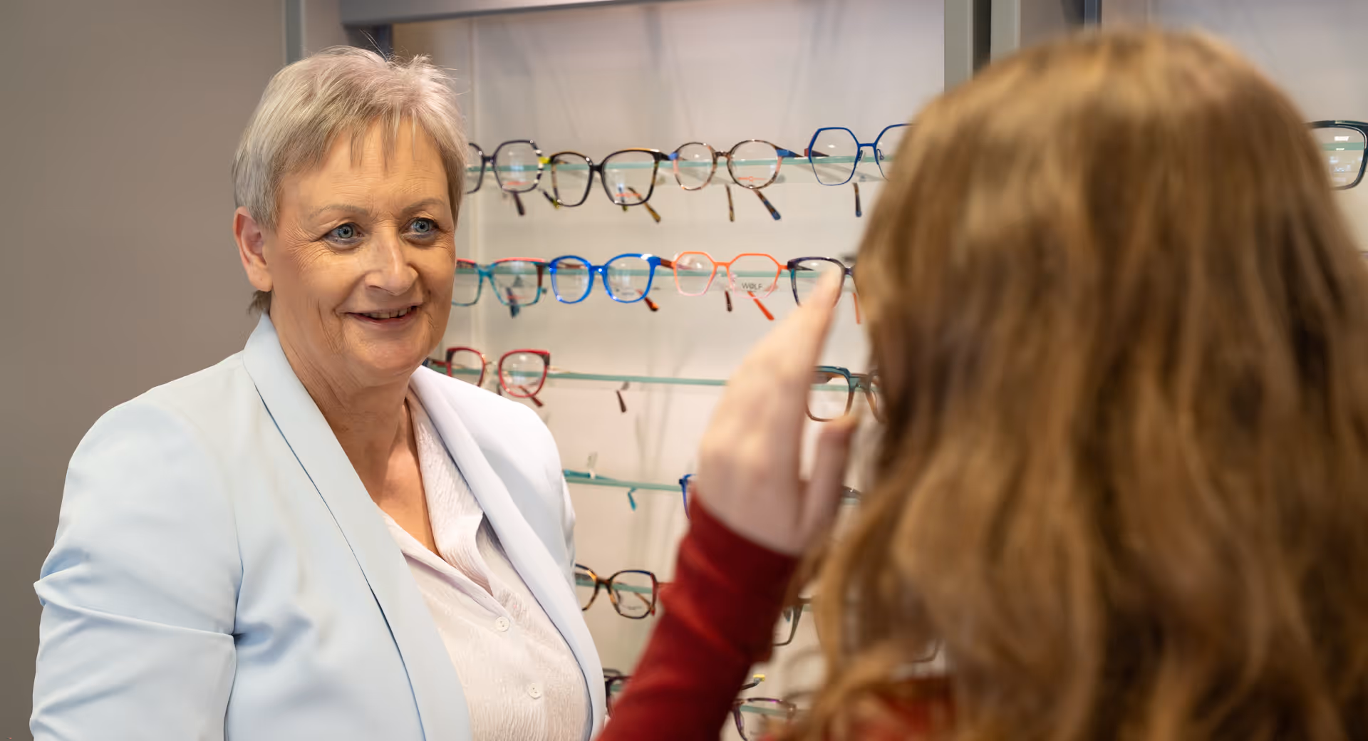 Optician helping customer choose glasses from colorful display