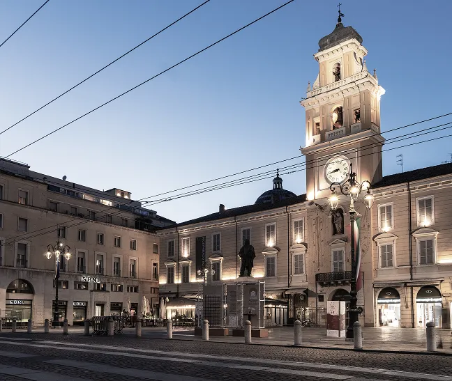 Piazza Garibaldi a Parma al crepuscolo, con la torre dell'orologio e il Palazzo del Governatore.