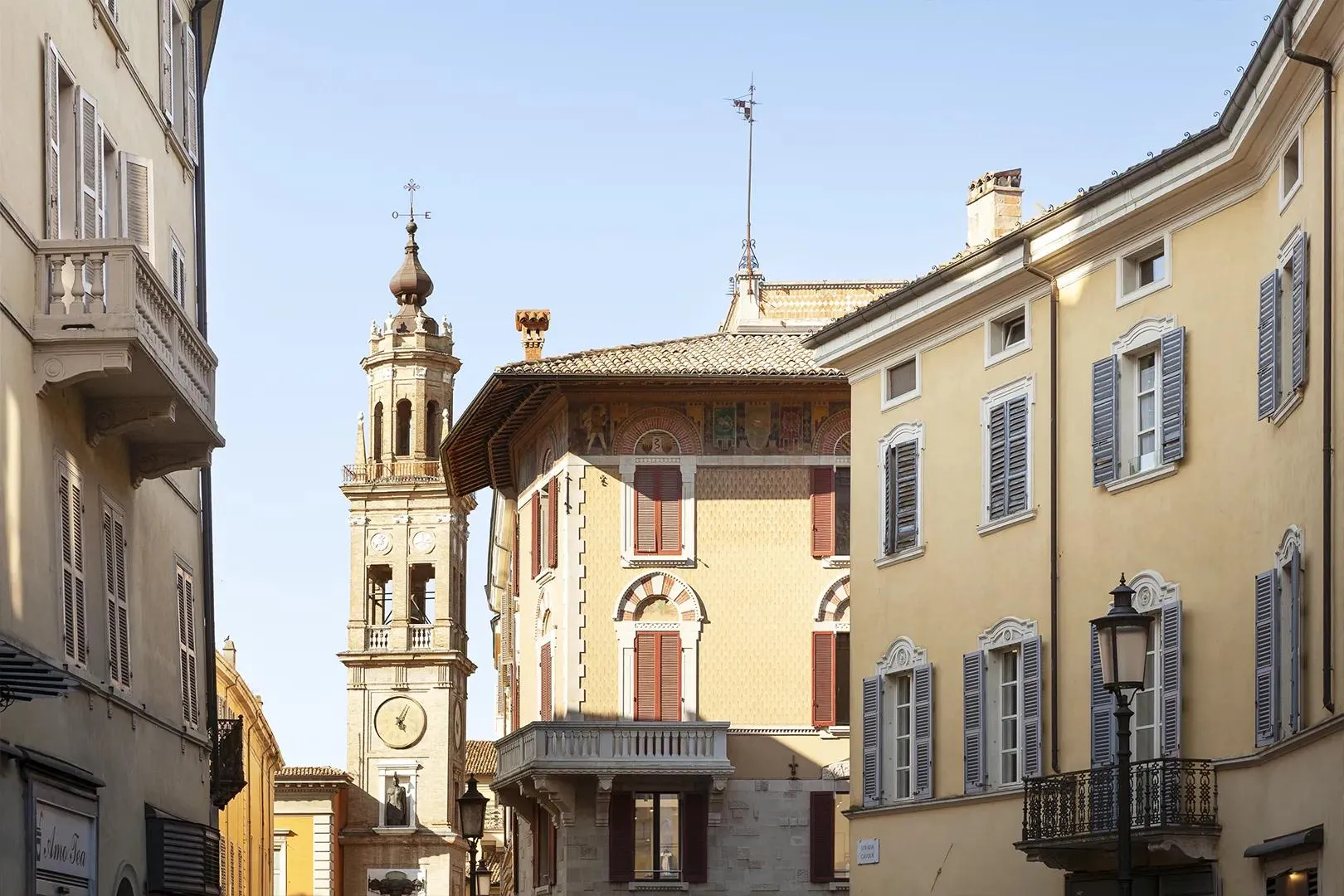 Via del centro di Parma con palazzi storici e una torre decorata.
