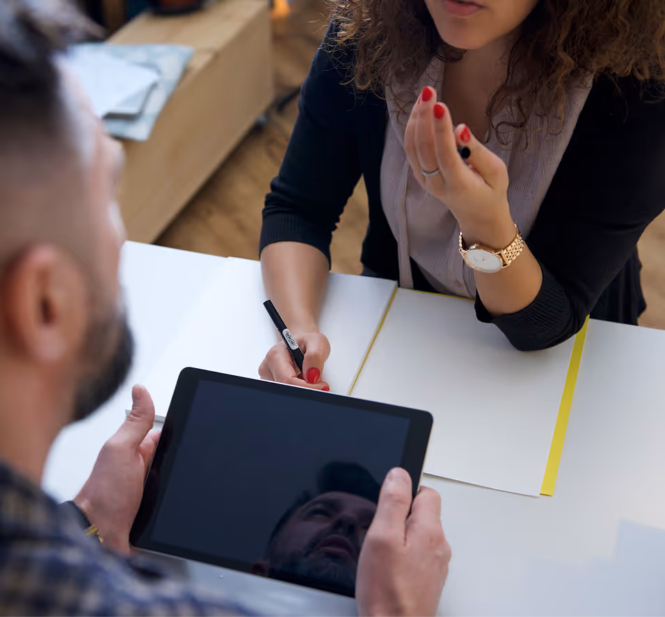 2 people having a user interview, one taking notes and another looking at an ipad