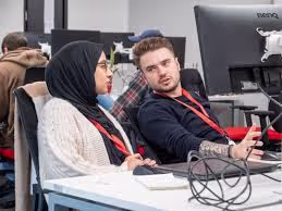 Two young people having a discussion at a computer desk