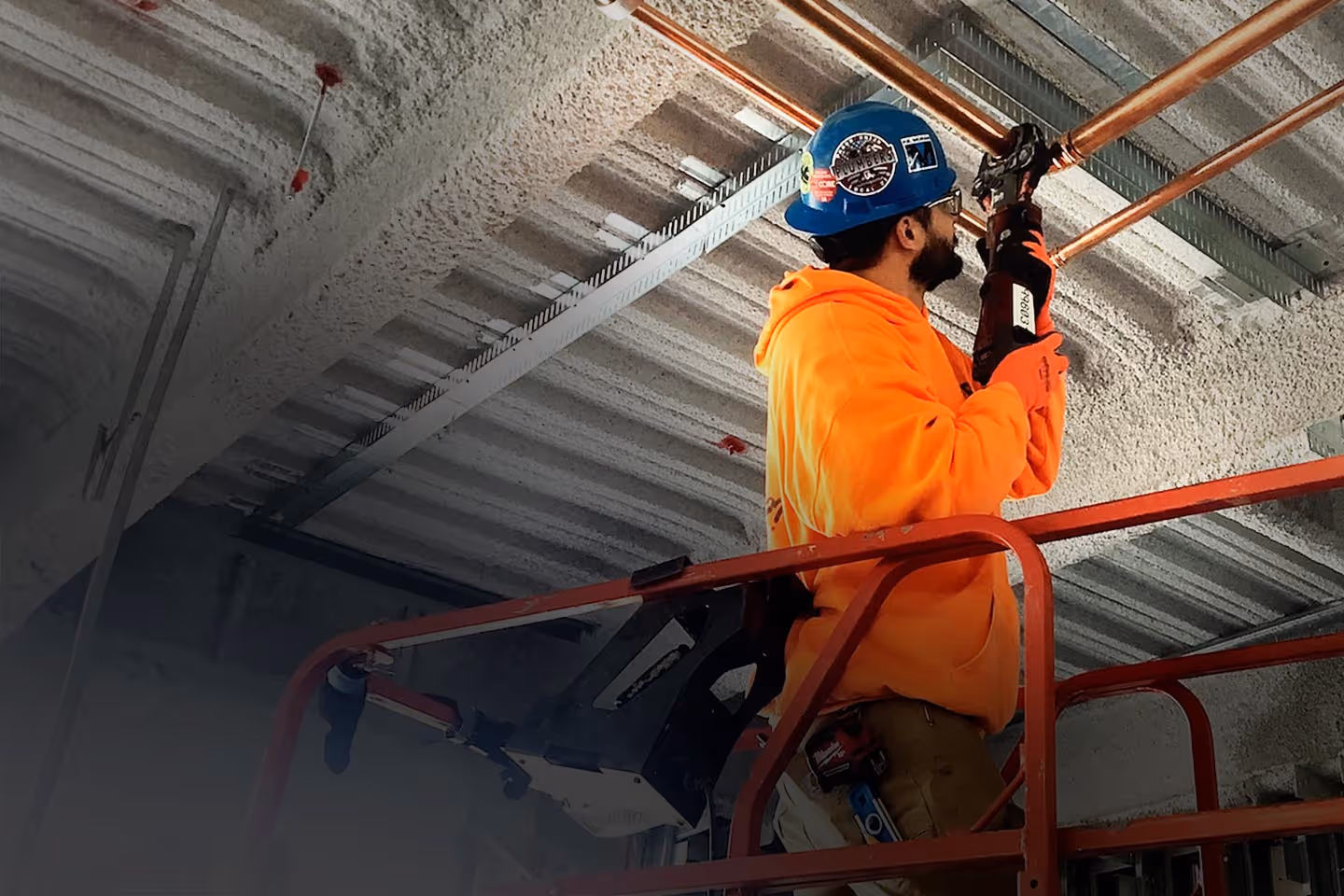 A plumber working on copper pipes on the ceiling