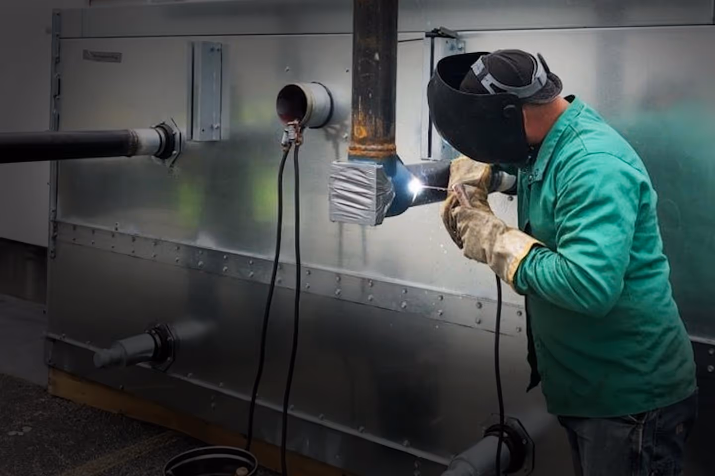 A man welding an industrial refrigerator