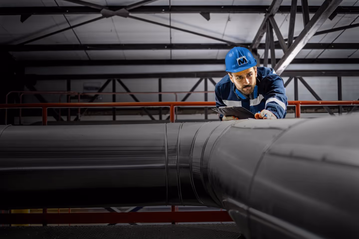 A man with a blue hardhat examining a large pipe