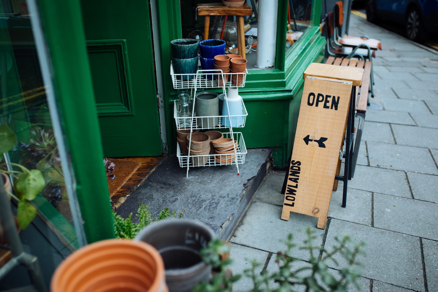 The lowlands shopfront with an open sign and some plant pots