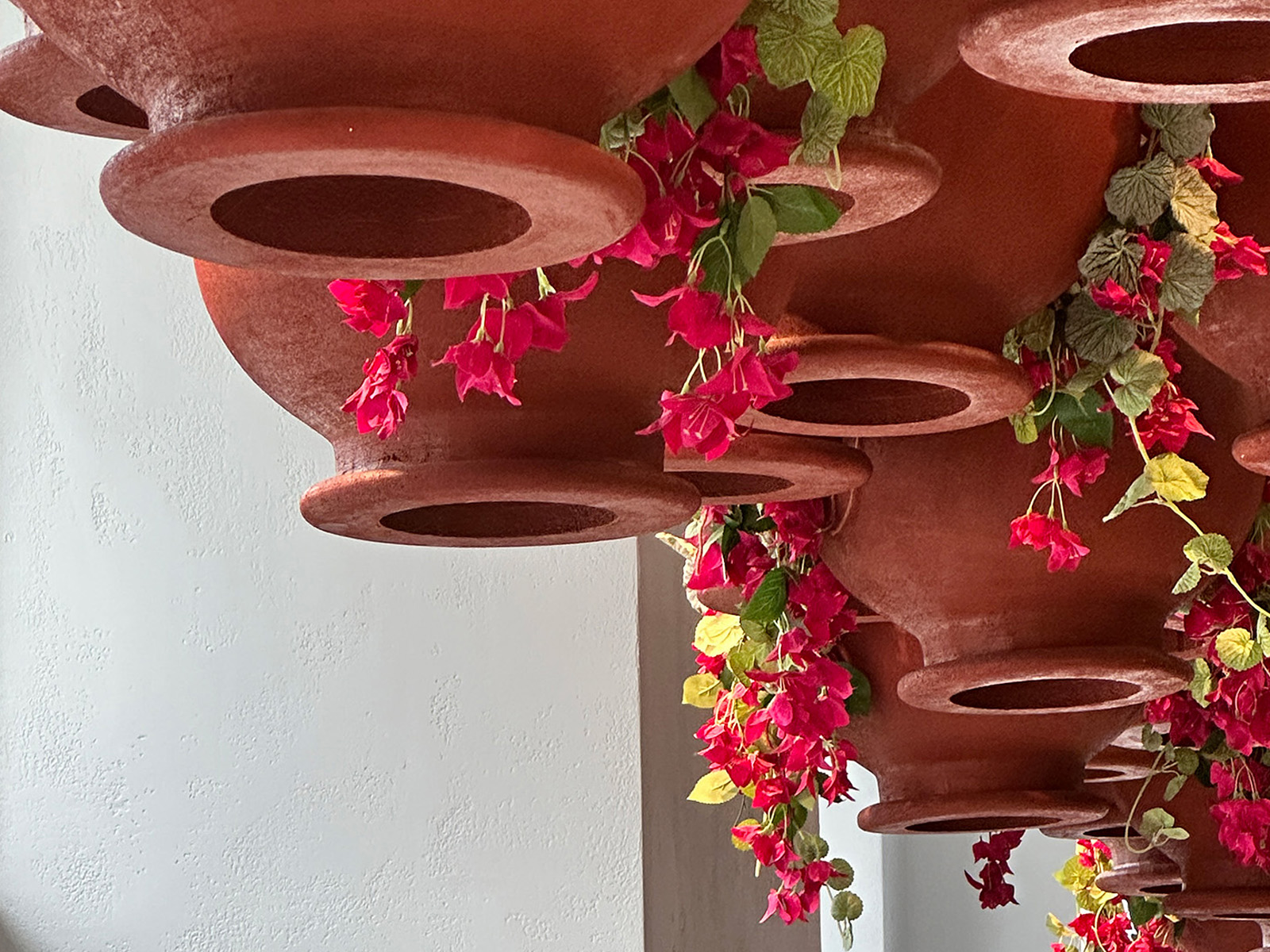 Folfol’s signature upside-down garden transforms traditional Syrian rooftop greenery into a dramatic ceiling installation of inverted terracotta pots and cascading bougainvillea, creating a memorable cultural experience.