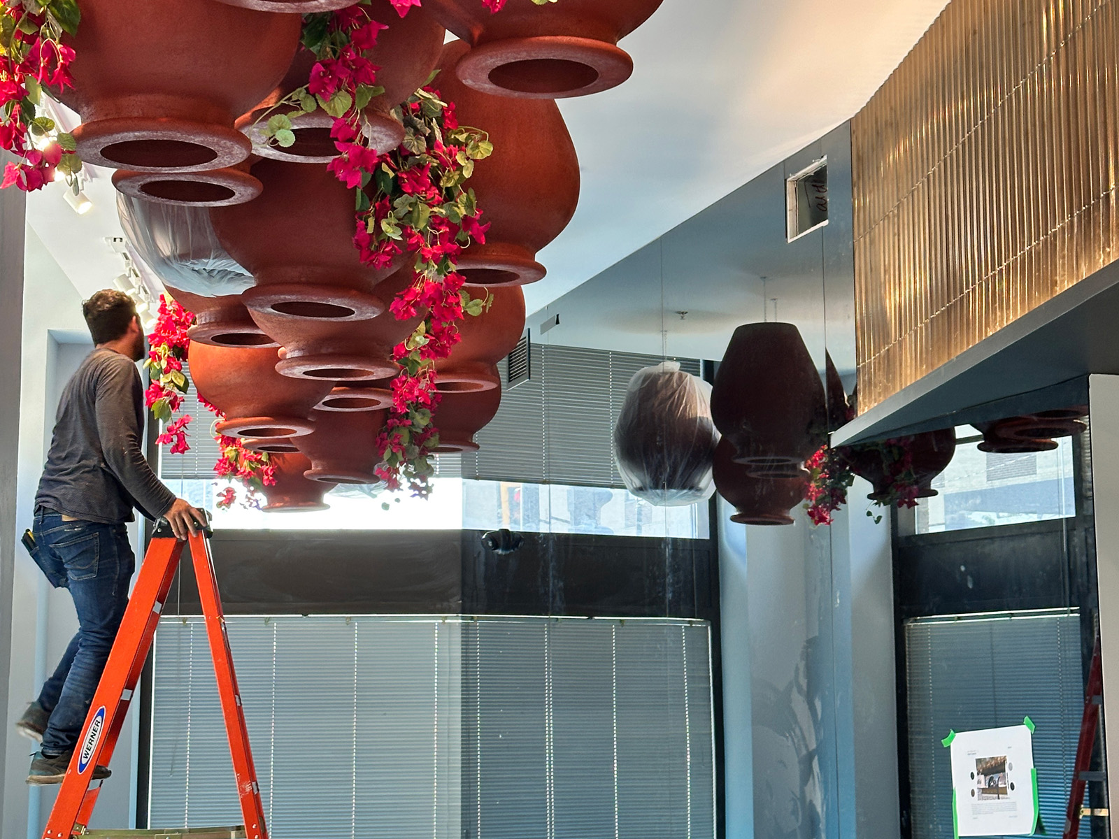Folfol’s signature upside-down garden transforms traditional Syrian rooftop greenery into a dramatic ceiling installation of inverted terracotta pots and cascading bougainvillea, creating a memorable cultural experience.