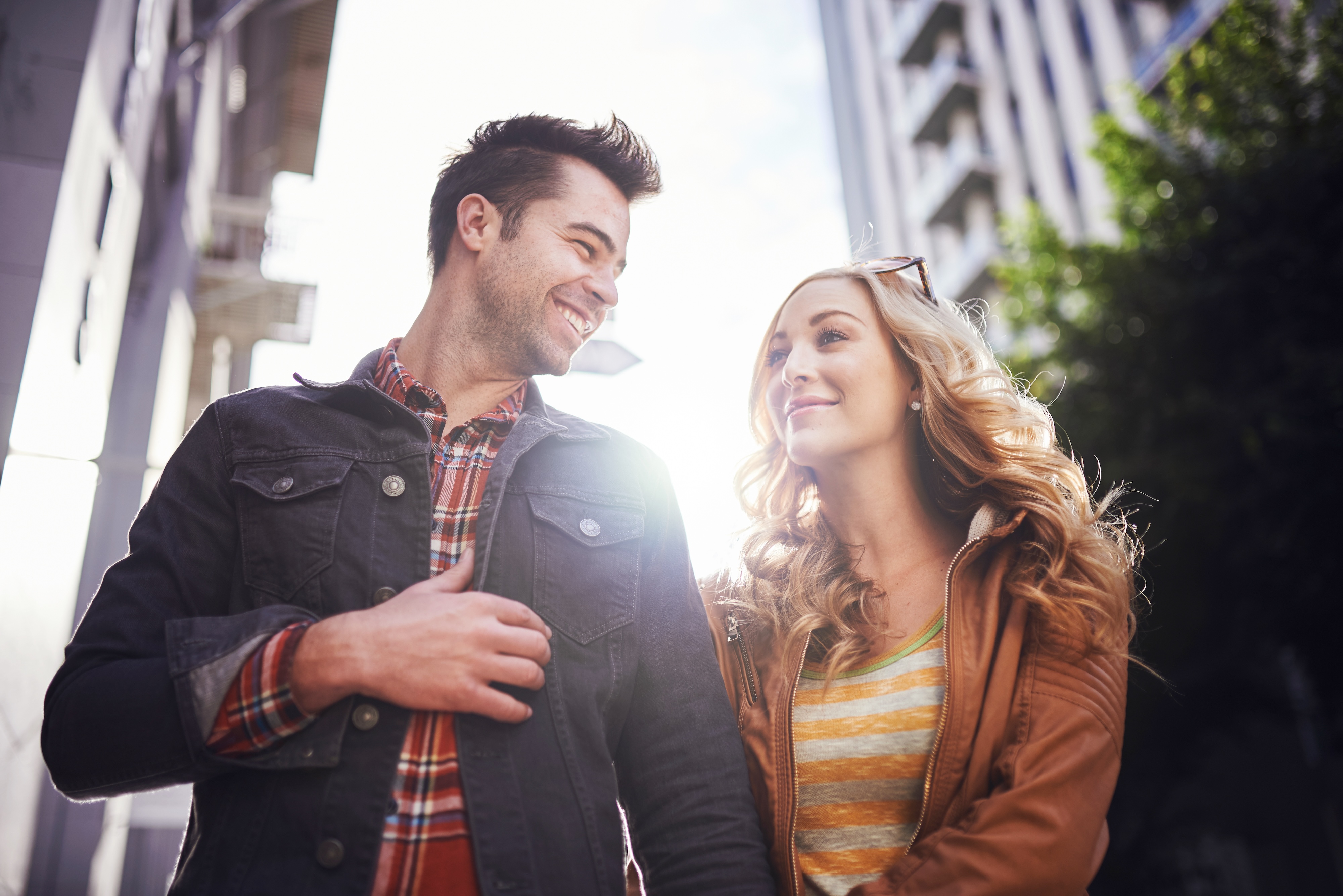 Happy couple smiling at each other while walking outdoors in an urban setting, representing the vibrant lifestyle near Crossing at 9th apartments in Salt Lake City