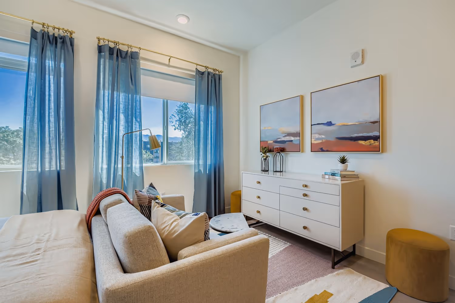 Furnished room with wood-style flooring and a large window offering views of distant mountains and city buildings, in an apartment at Crossing at 9th in Salt Lake City.