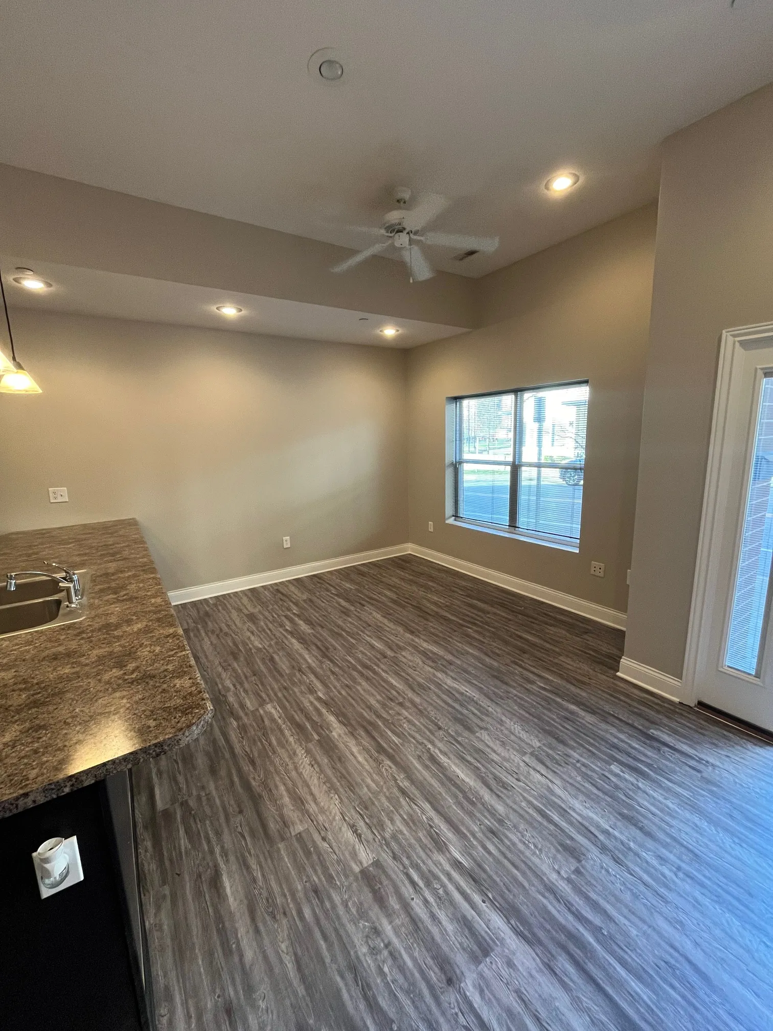 Spacious open-concept living area at 5 North featuring wood-style flooring, neutral walls, recessed lighting, and a ceiling fan.