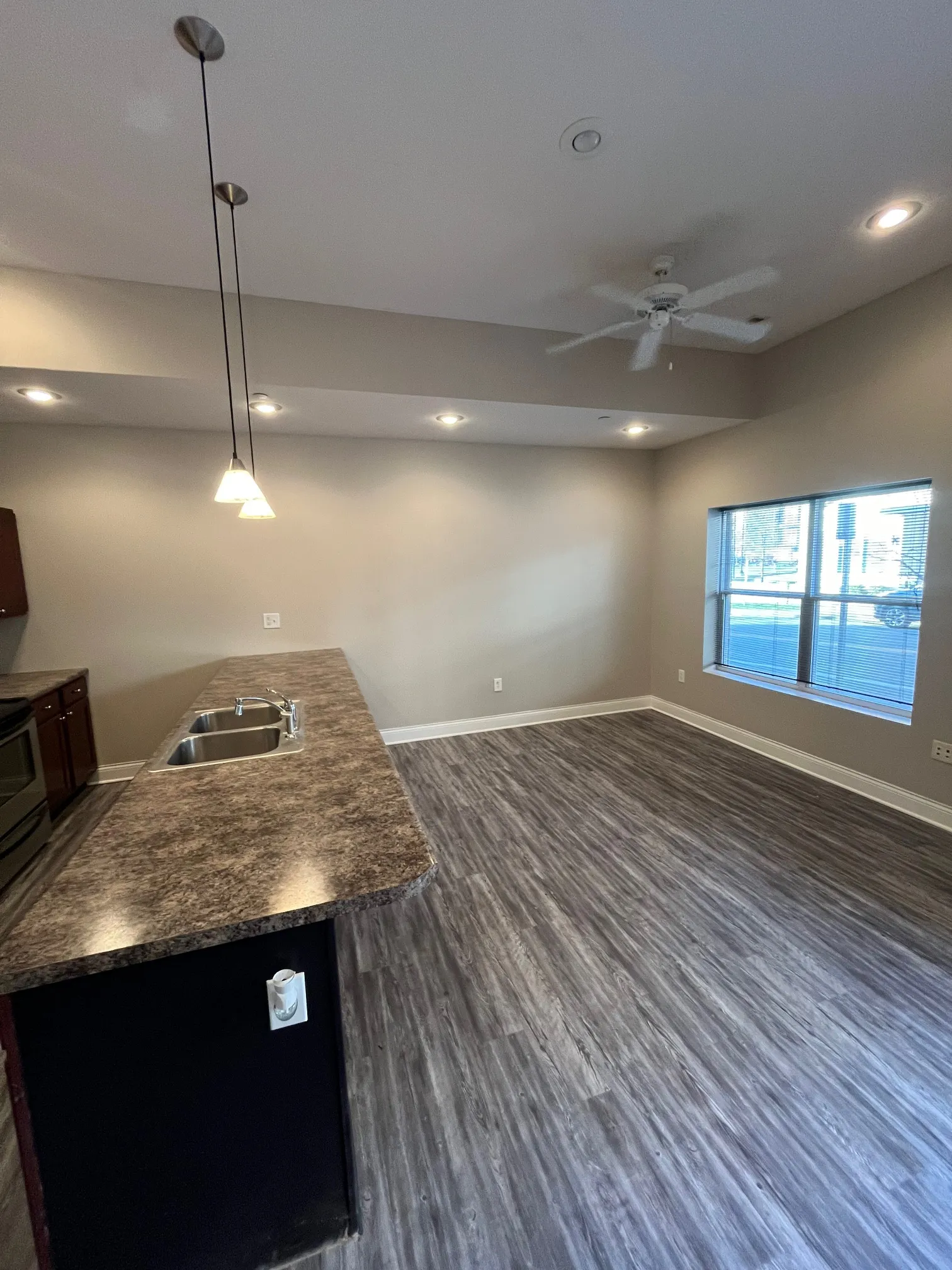 Bright living area at 5 North with high ceilings, recessed lighting, ceiling fan, and large window providing natural light.