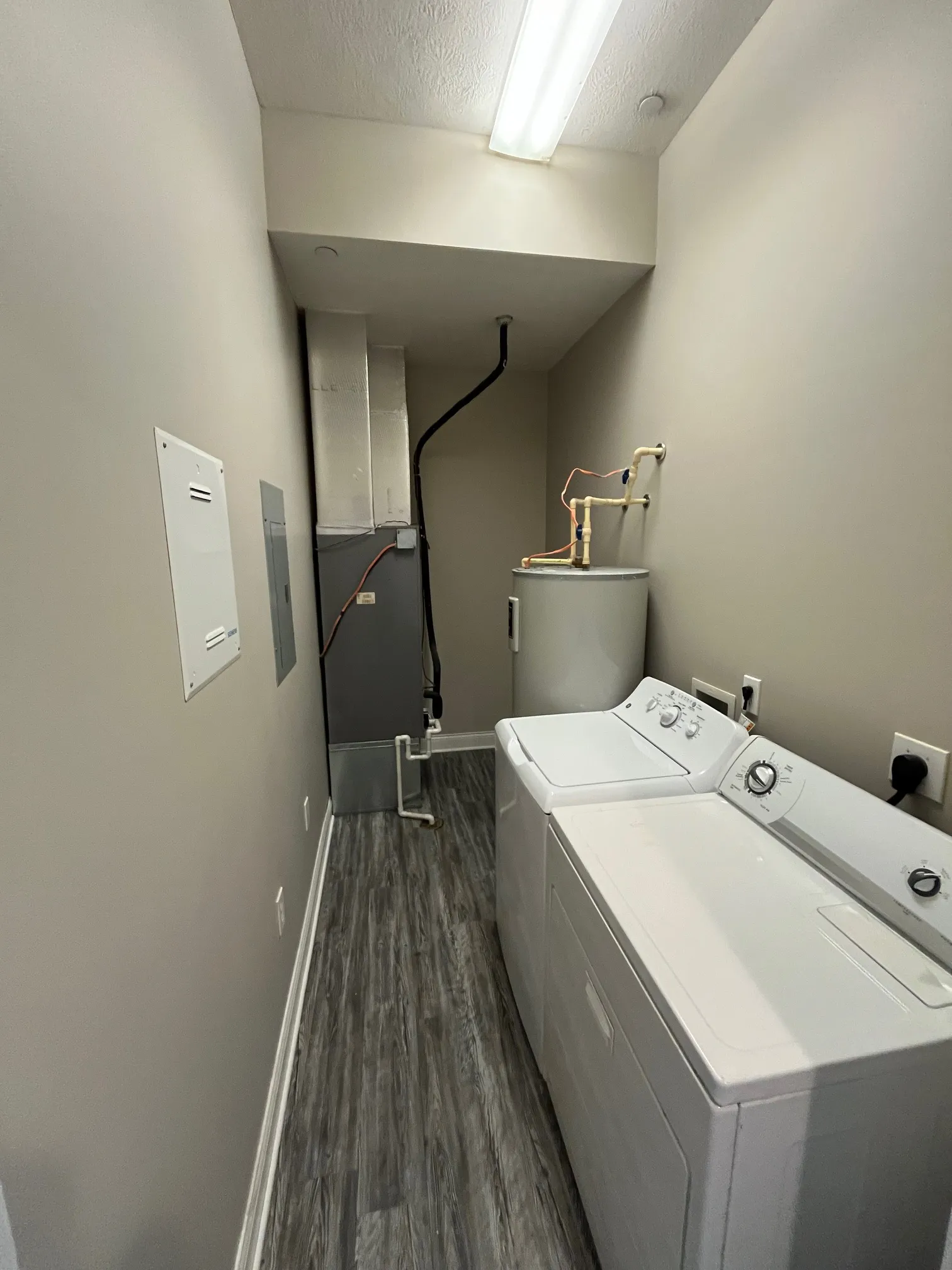 In-unit laundry room at 5 North apartments featuring a side-by-side washer and dryer set with wood-style flooring.