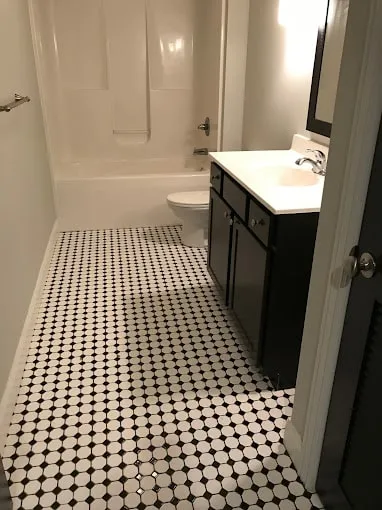 Apartment bathroom at 7 Ten featuring black and white hexagonal floor tile and a dark wood vanity.