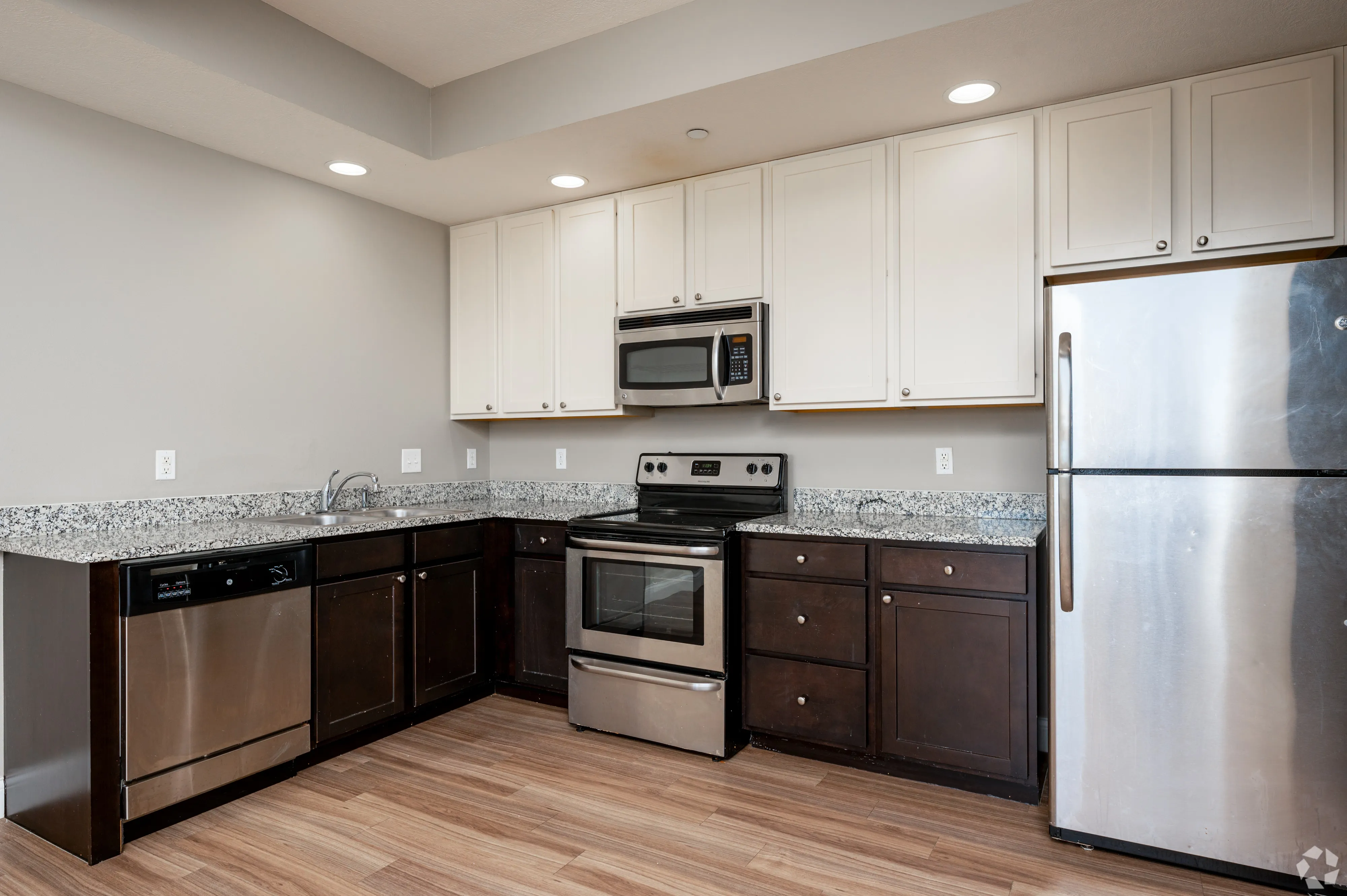 Kitchen area at 7 Ten featuring dark lower cabinets, white upper cabinets, and a stainless steel dishwasher.