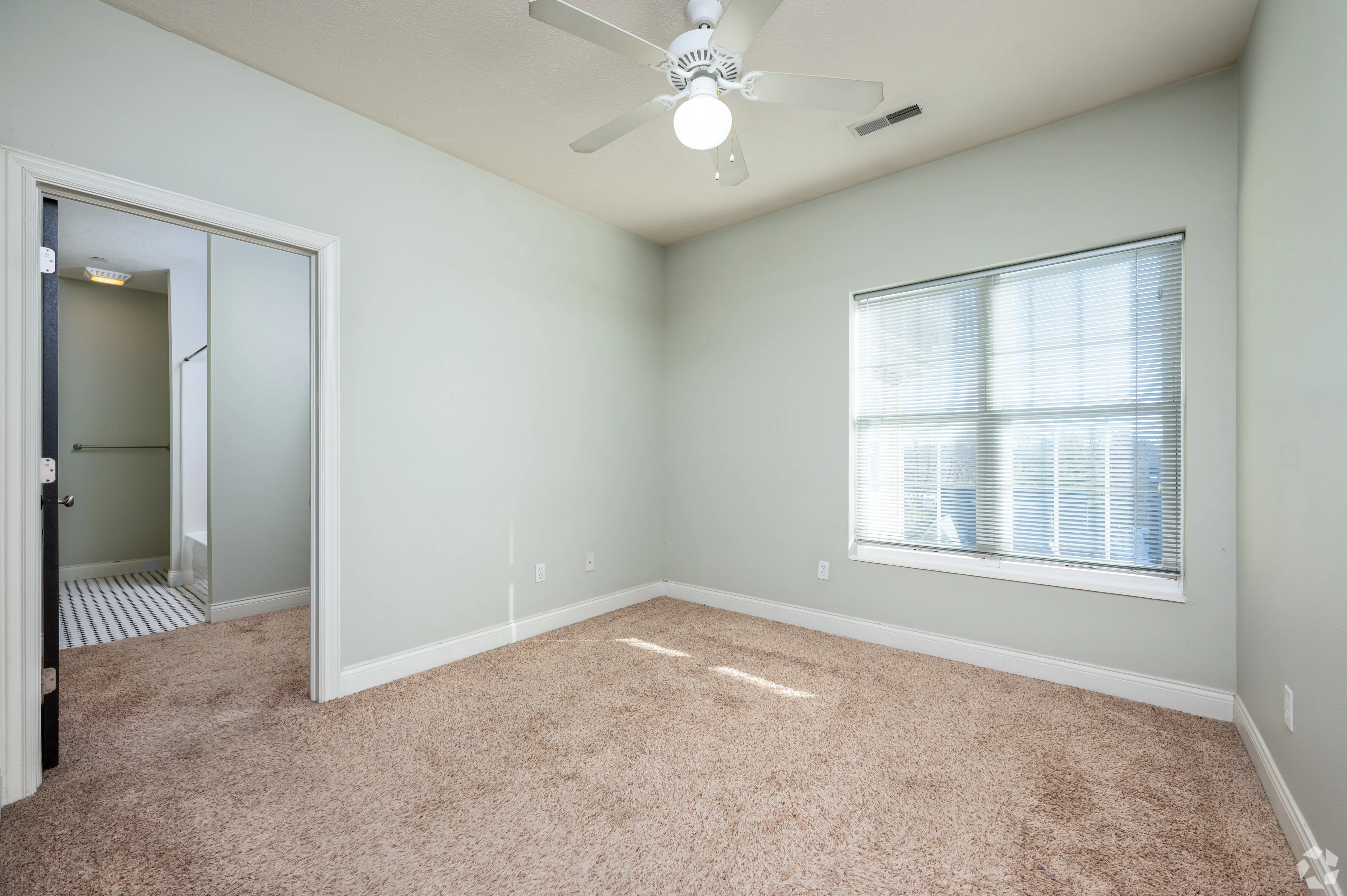 Natural light fills a 7 Ten bedroom with neutral tones, featuring a white ceiling fan and views of the Bloomington neighborhood.