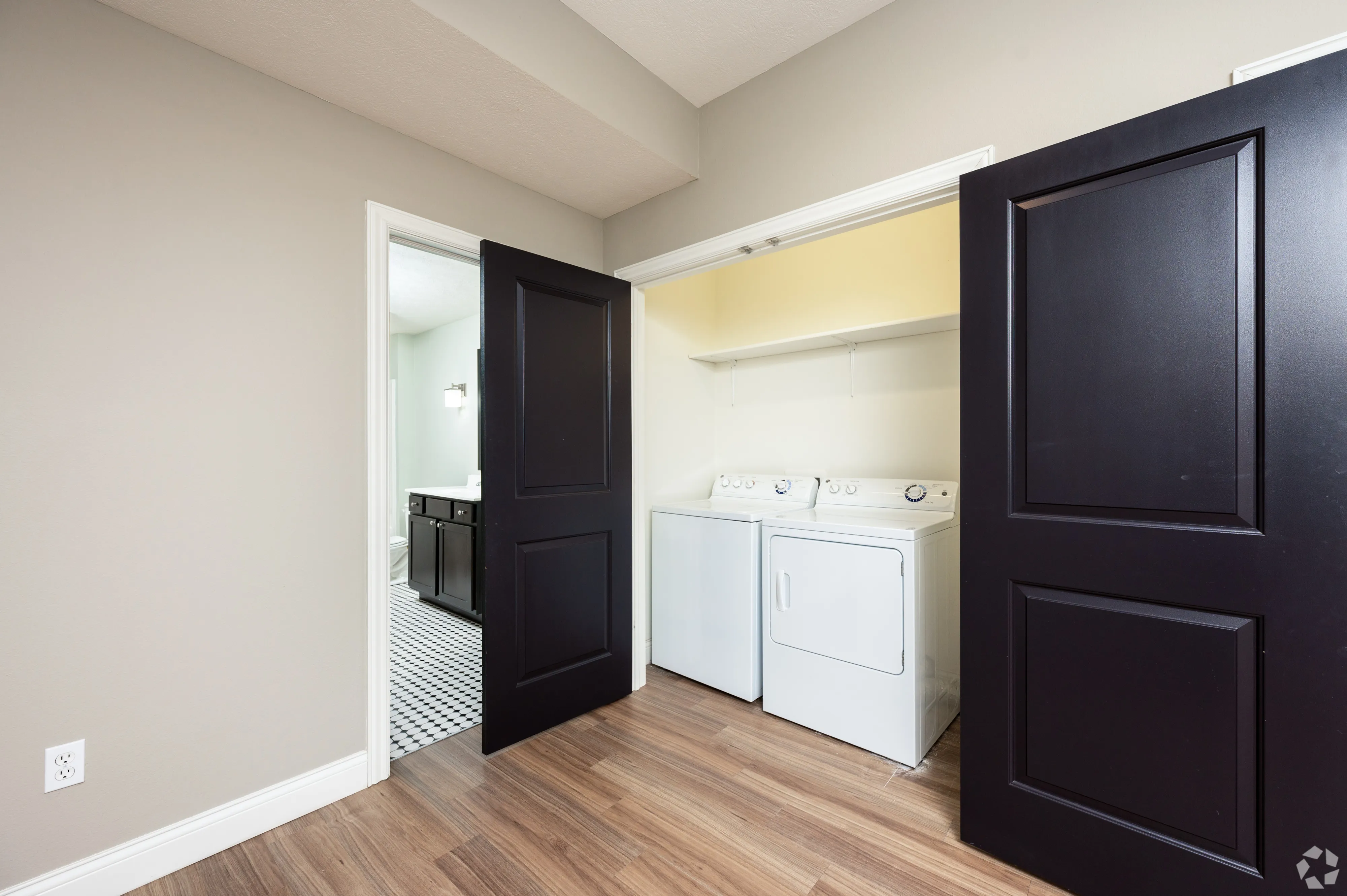 In-unit laundry closet at 7 Ten featuring a side-by-side washer and dryer set behind dark wood doors.