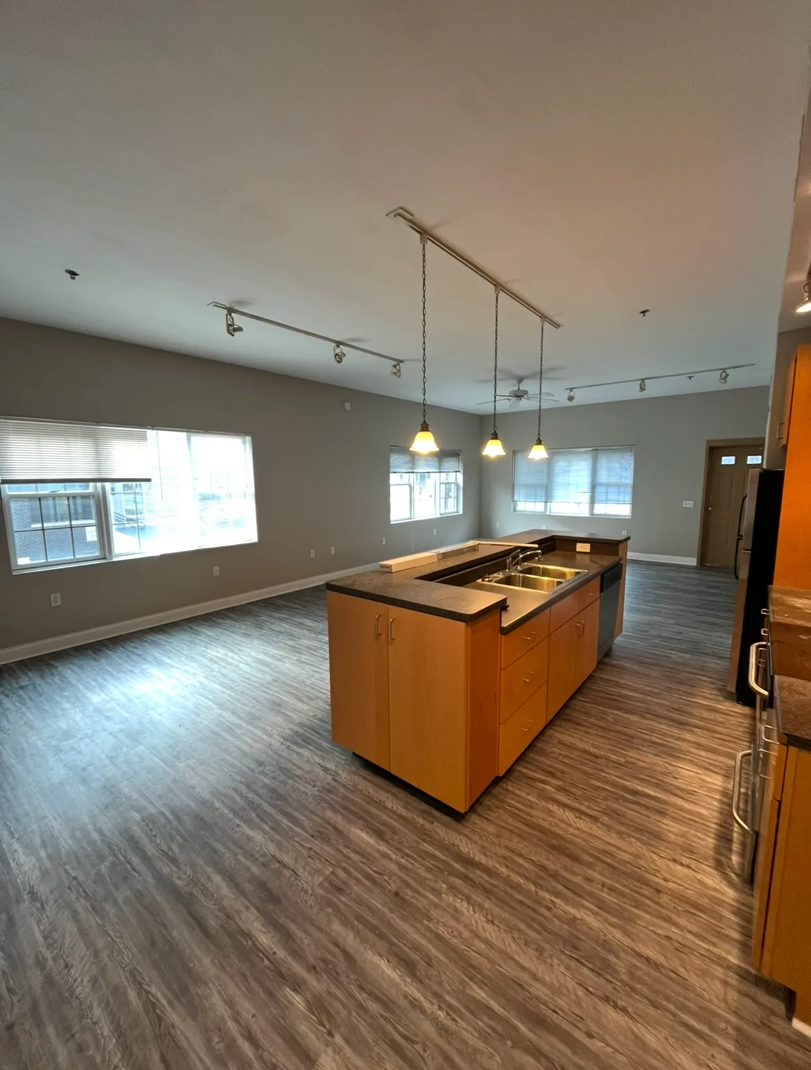 Open-concept kitchen and living area featuring a large tiered island with light wood finishes and wood-style flooring.