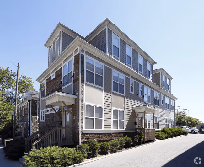Exterior of The Northern apartment building in Bloomington, featuring a mix of neutral siding, brick accents, and a wooden staircase entrance.