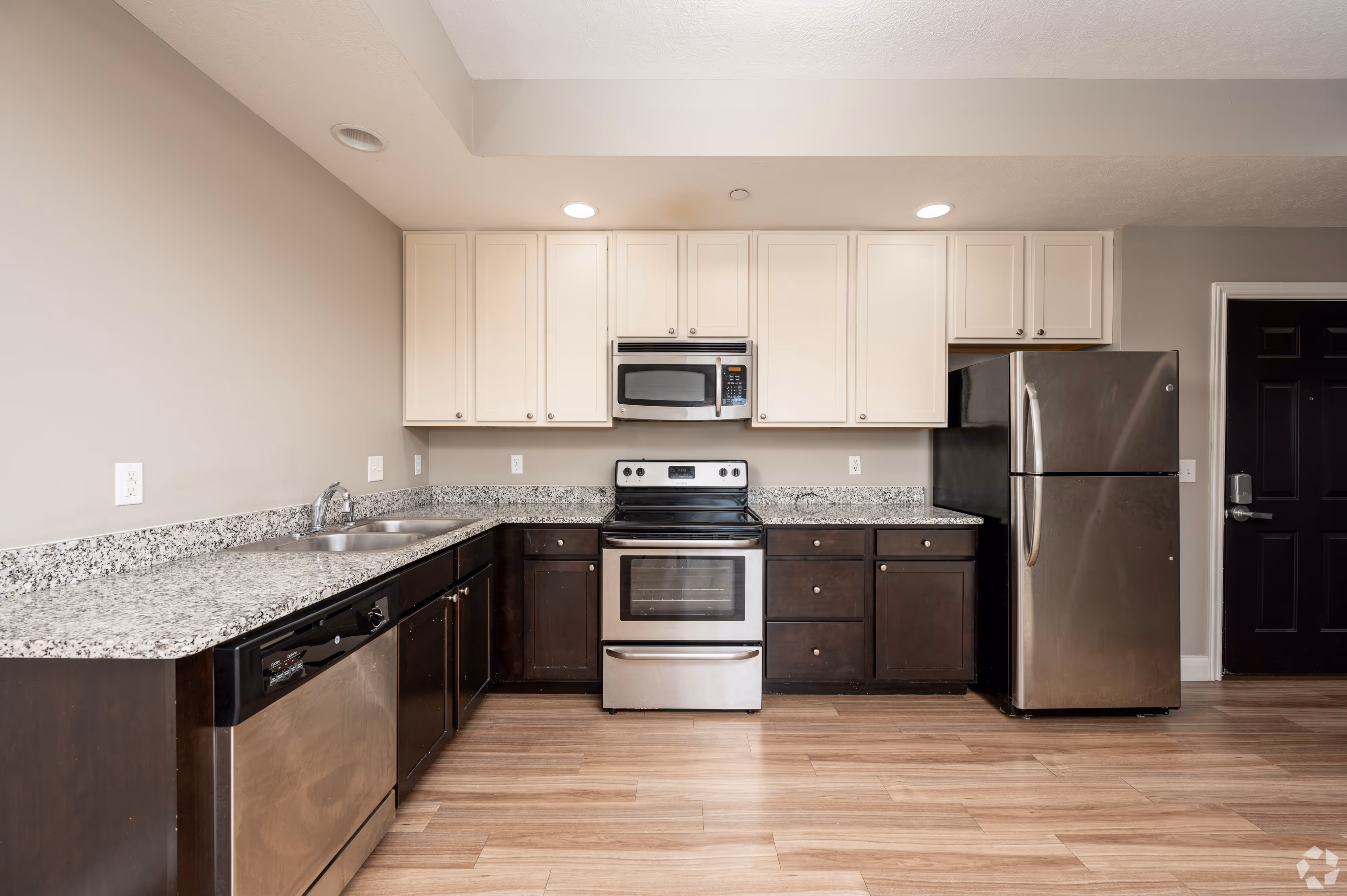 Modern kitchen at 7 Ten with two-tone cabinetry, granite-style countertops, and stainless steel appliances.