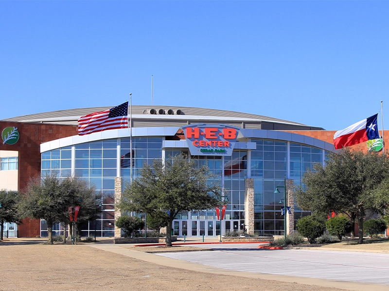 Sunset illuminates a rustic wooden bridge over a calm river, surrounded by lush greenery and tranquil waters in Cedar Park Texas.