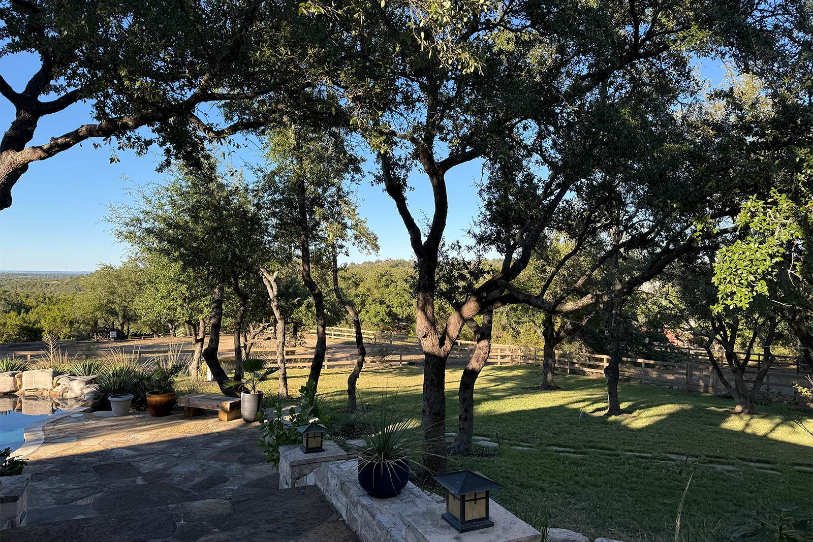 A serene riverside scene in Marble Falls Texas featuring a vivid green park lawn, a bridge spanning the water, and a partly cloudy blue sky.