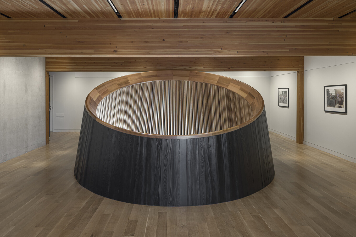The other floor with a wooden mass timber ceiling and posts and beams. The circular ceiling goes up into the ceiling with different wood pieces in various shades of natural color.