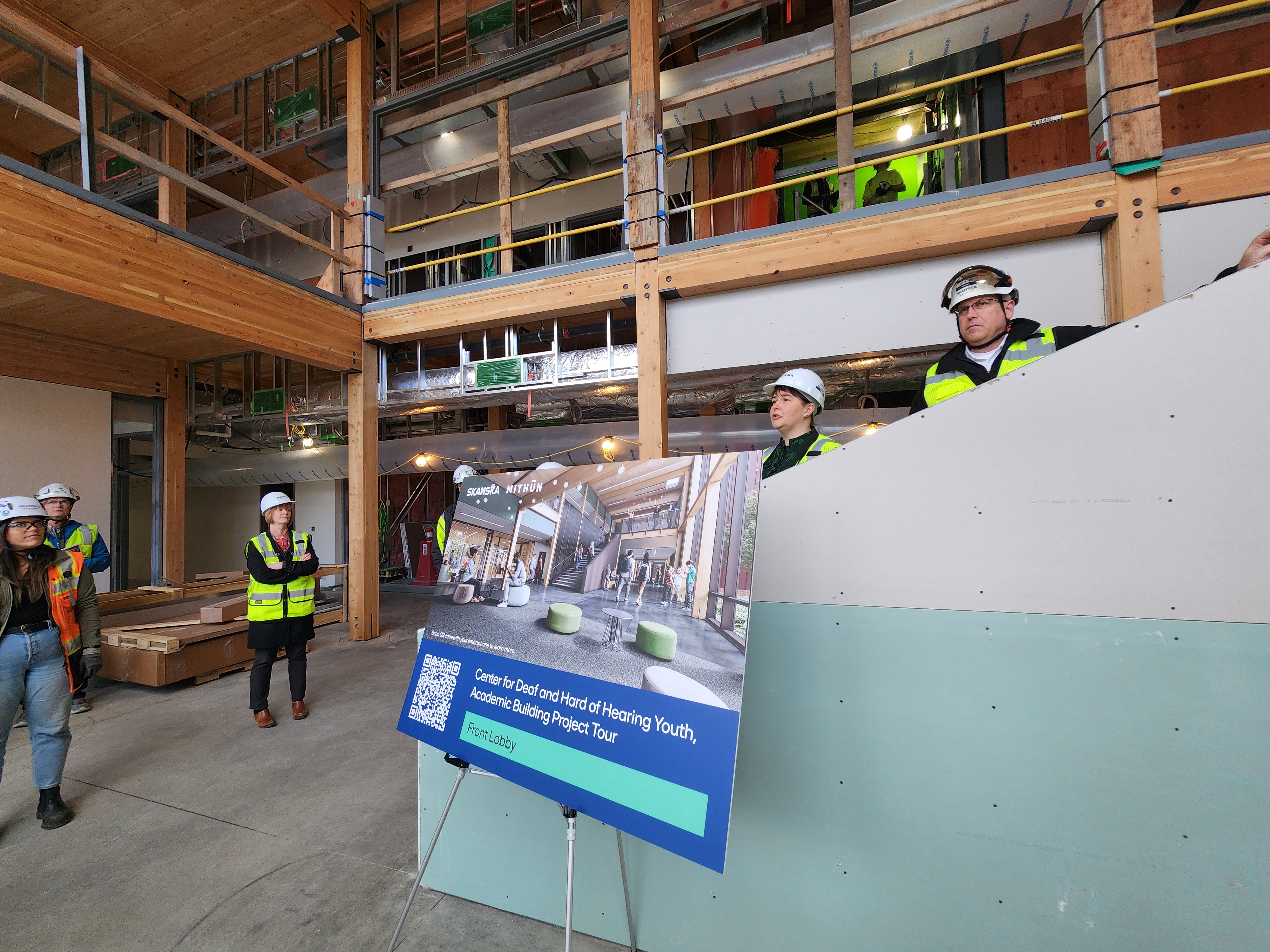 During a tour of the building, Skanska and the Washington State Department of Enterprise Services (DES) take people around to share the mass timber and angles worked on to accommodate students at the school and this is looking towards the reception desk and middle staircase. 
