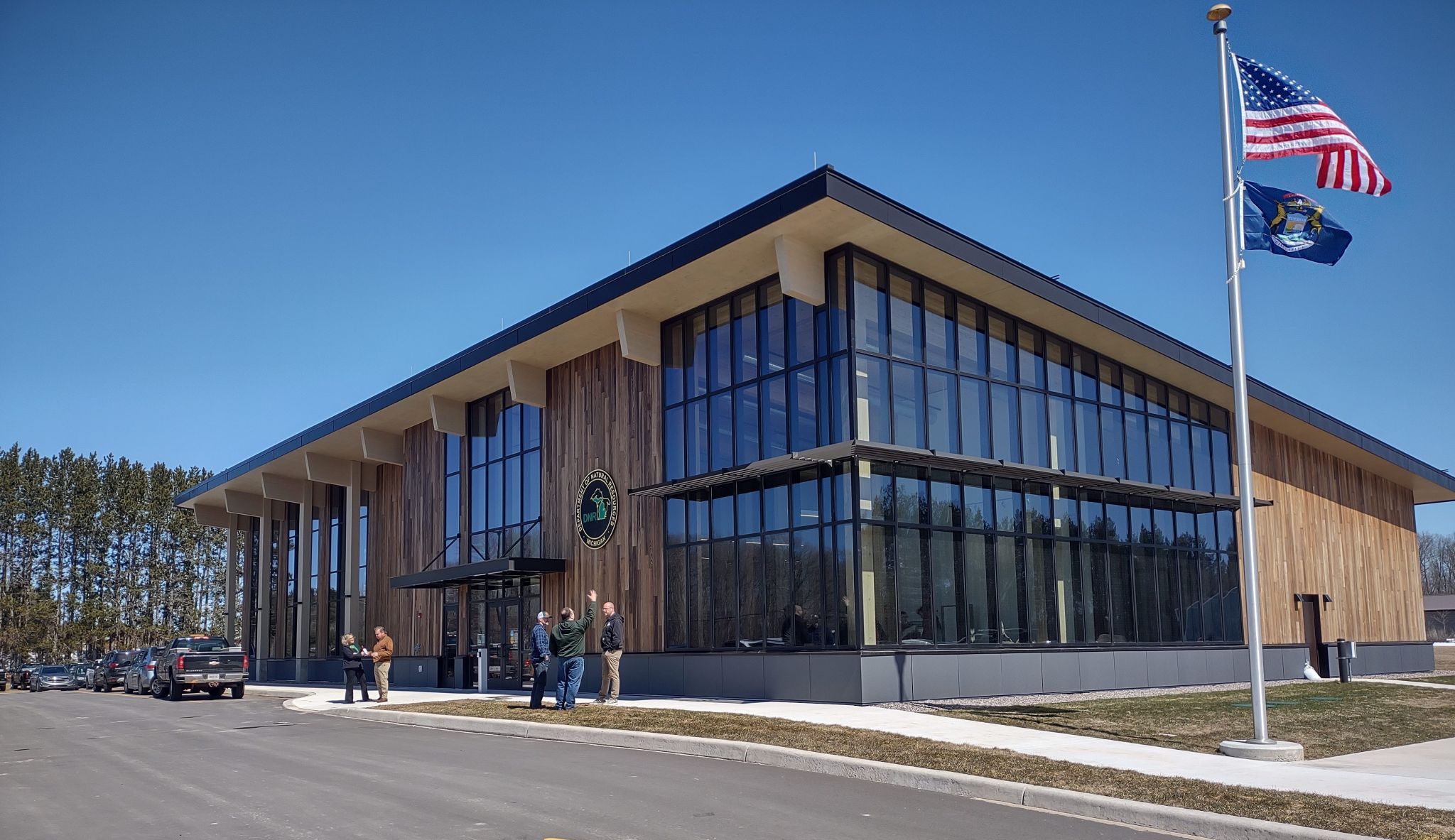 A grand opening celebration with people standing outside of the newly built Michigan Department of Natural Resources mass timber building.
