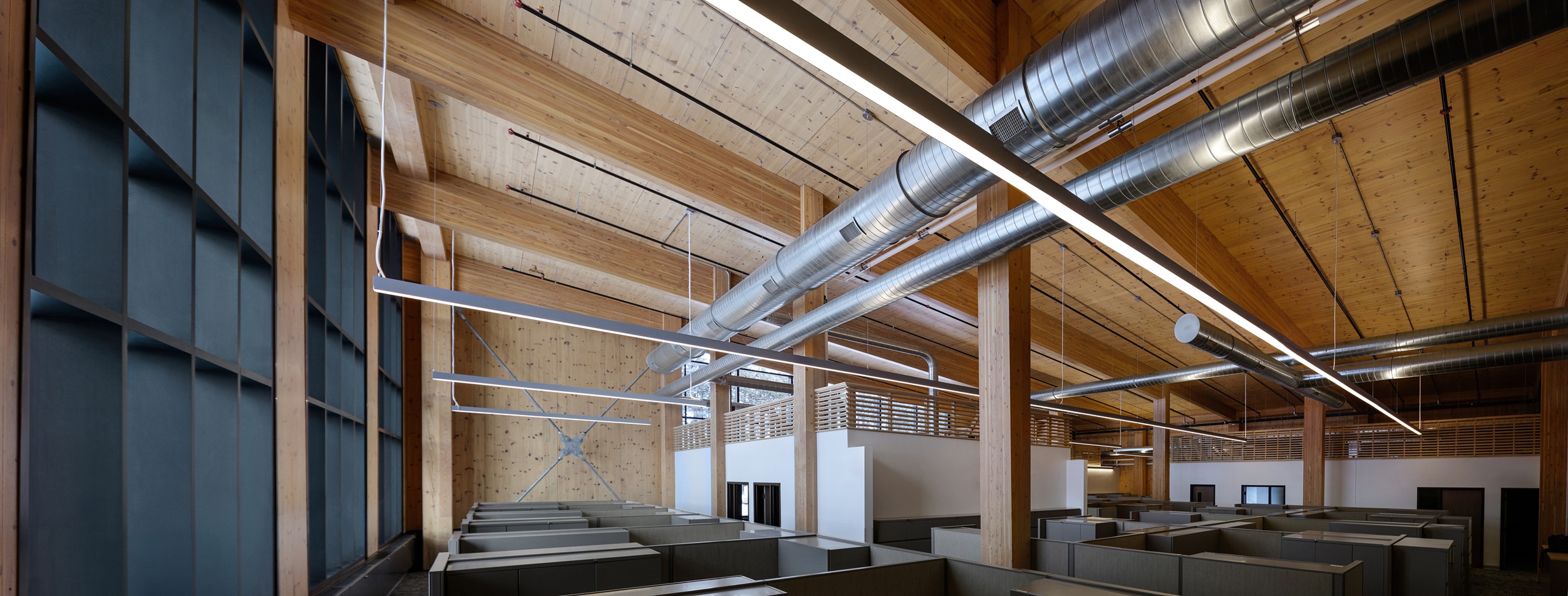 The inside of the Michigan State Department of Natural Resources building with exposed duct work and pipes coming from the exposed CLT mass timber ceiling.