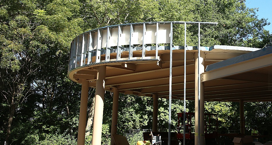 A circle base on the outside of a mass timber building with steel girders going up for support.