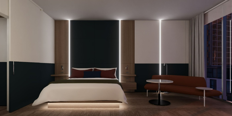 A well lit bedroom and a chair and a sofa with accent lights and bedcoverings.