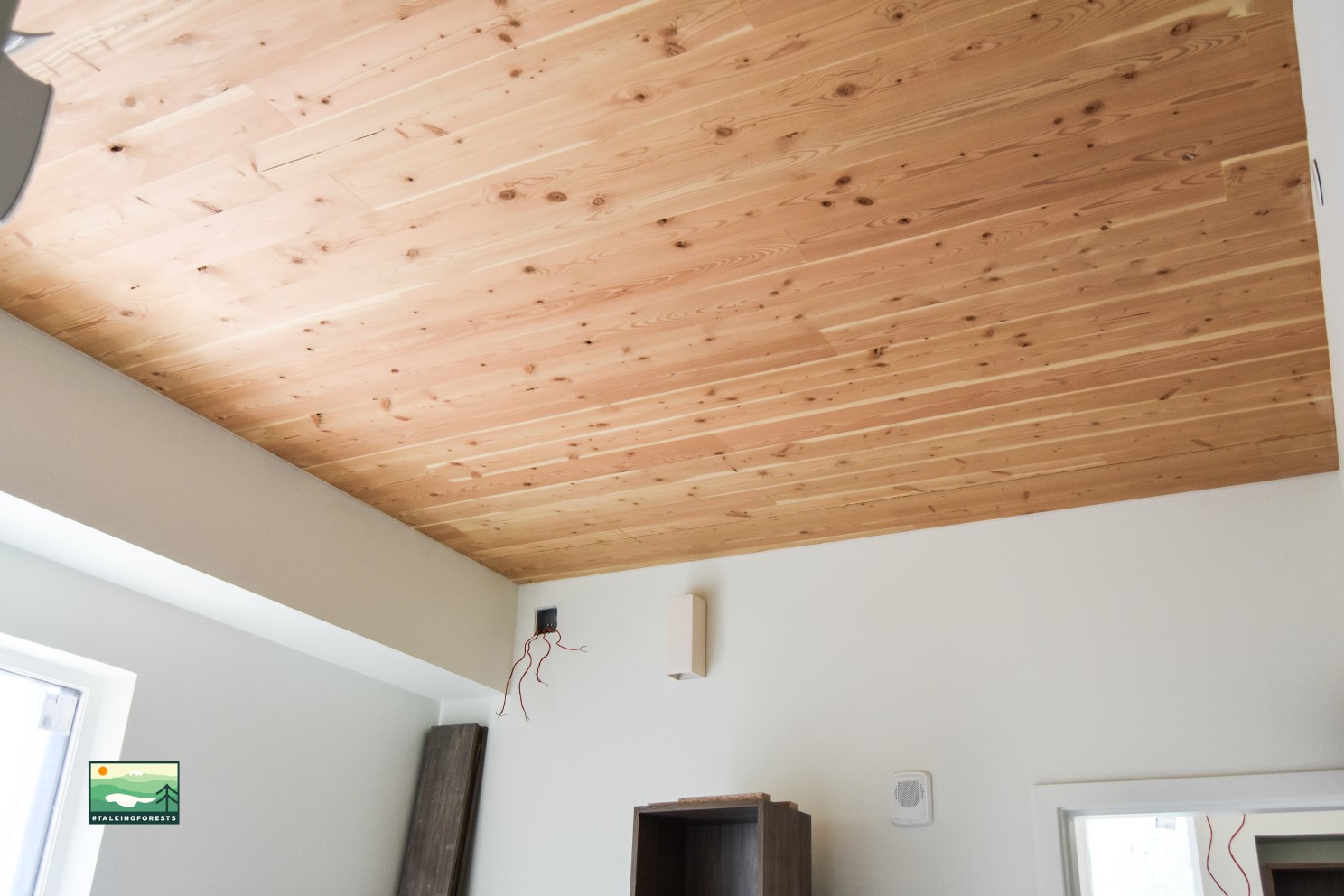 Inside a living unit with exposed ceilings made of mass timber and white walls with appliances coming in. Wiring is still exposed due to the building being under construction still.