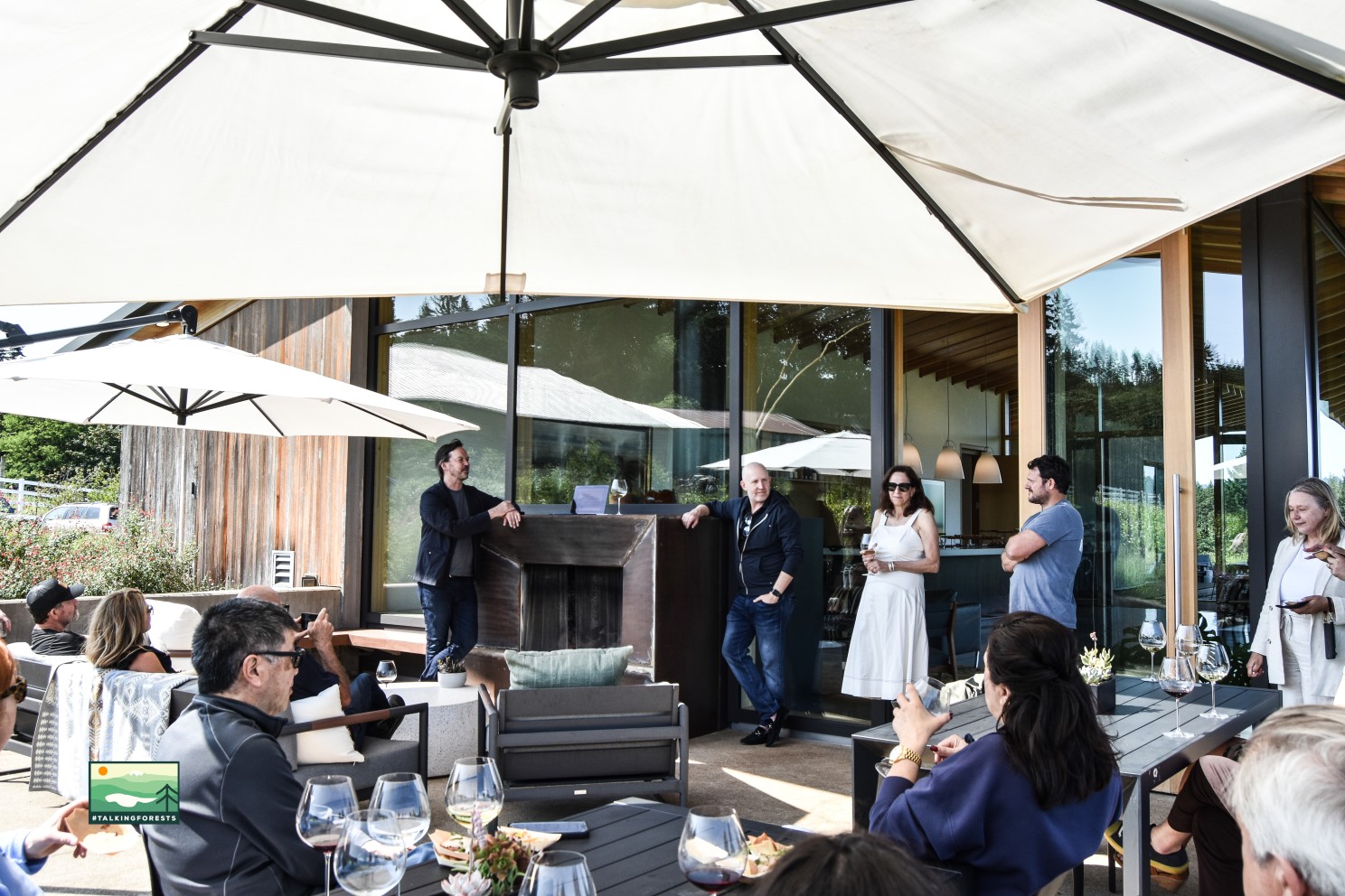 Thomas robinson from LEVER Architecture, Galen Hagerty from L'Angolo Estate Winery, James Leasure, 2025 PDX Modern Home Tour Producer, and guests sitting on the outdoor patio with comfortable seating and wine. 