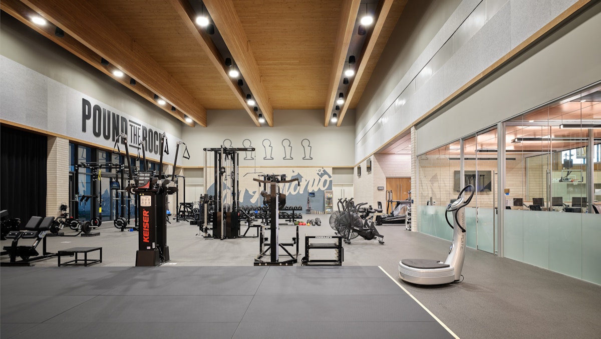 A fitness center room with exposed mass timber ceilings. Equipment around the room for different exercise needs. 