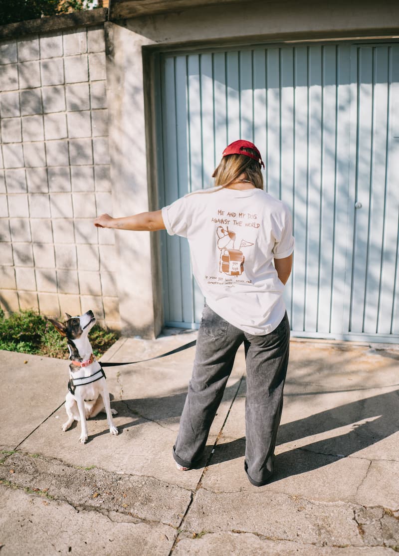 Owner with her back faced toward the camera giving a treat to her dog