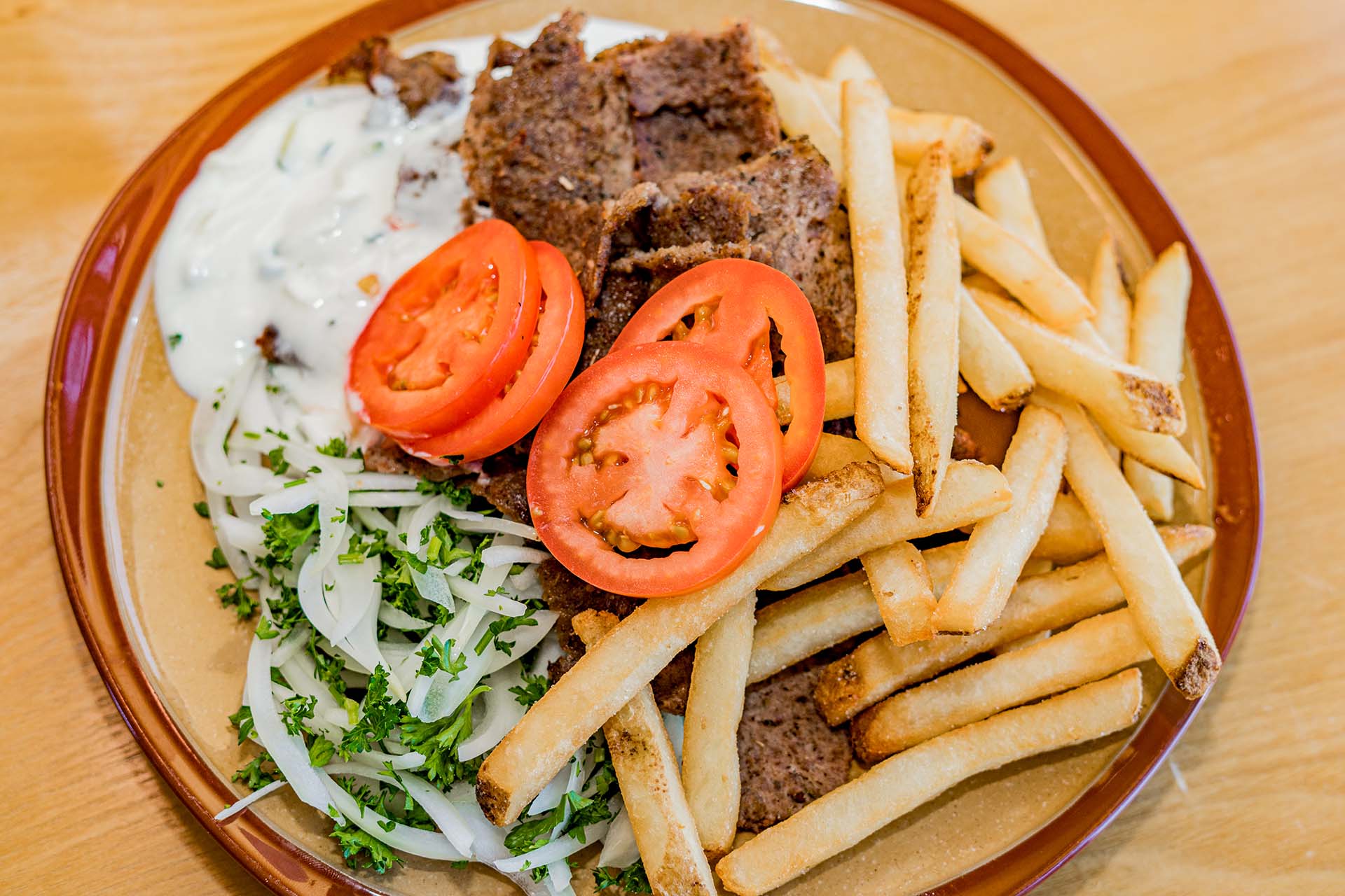 A plate of food with a sliced tomato, french fries, and meat.