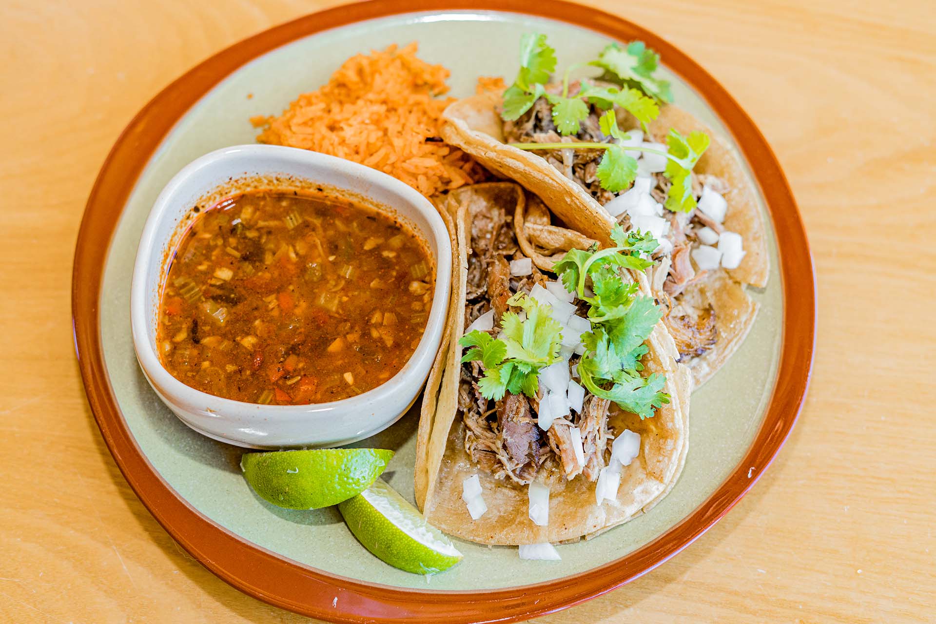 A plate of food with a bowl of soup and two tacos.